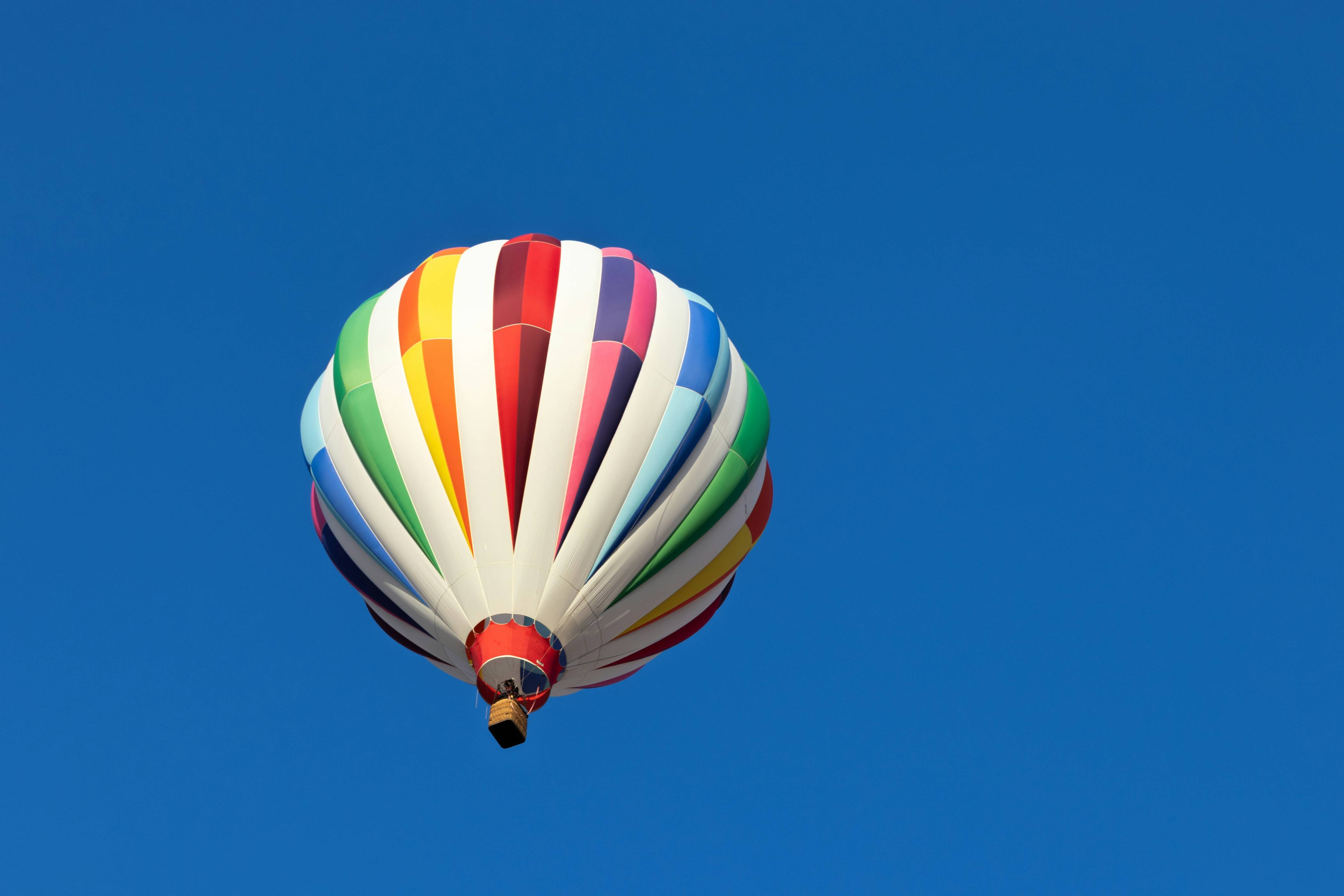 A colorful hot air balloon flying through a blue sky