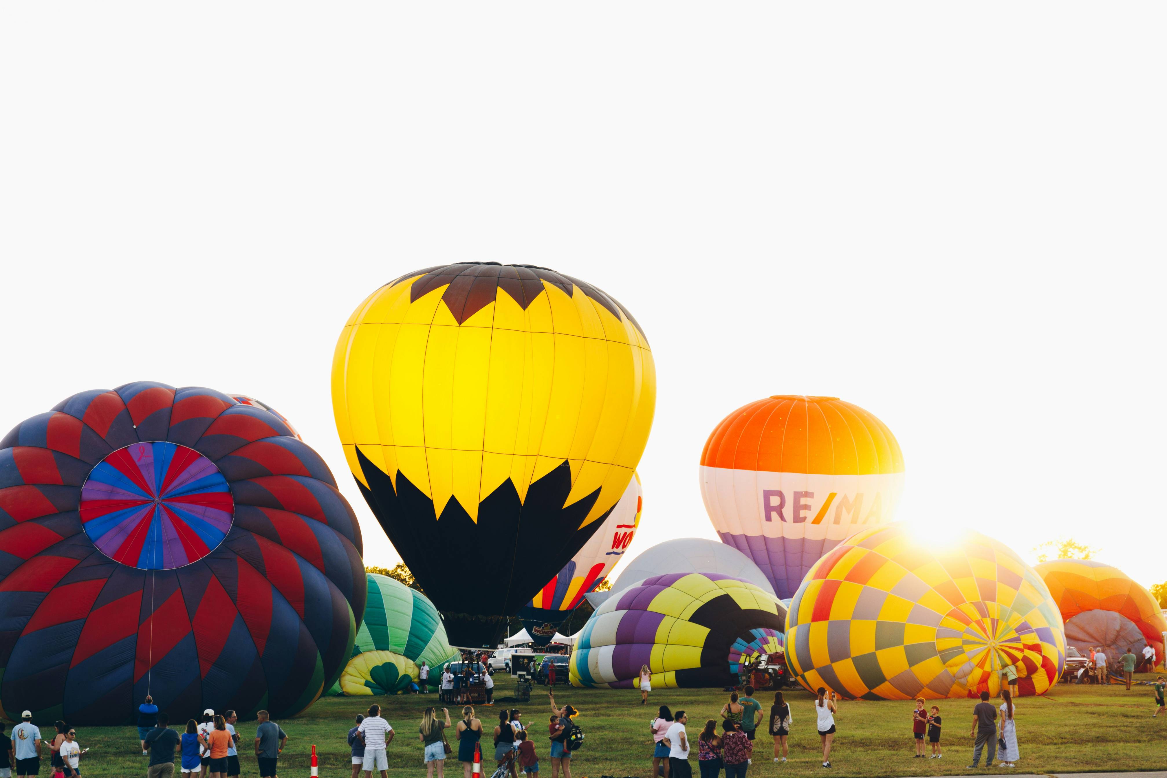 A group of people standing around a bunch of hot air balloons