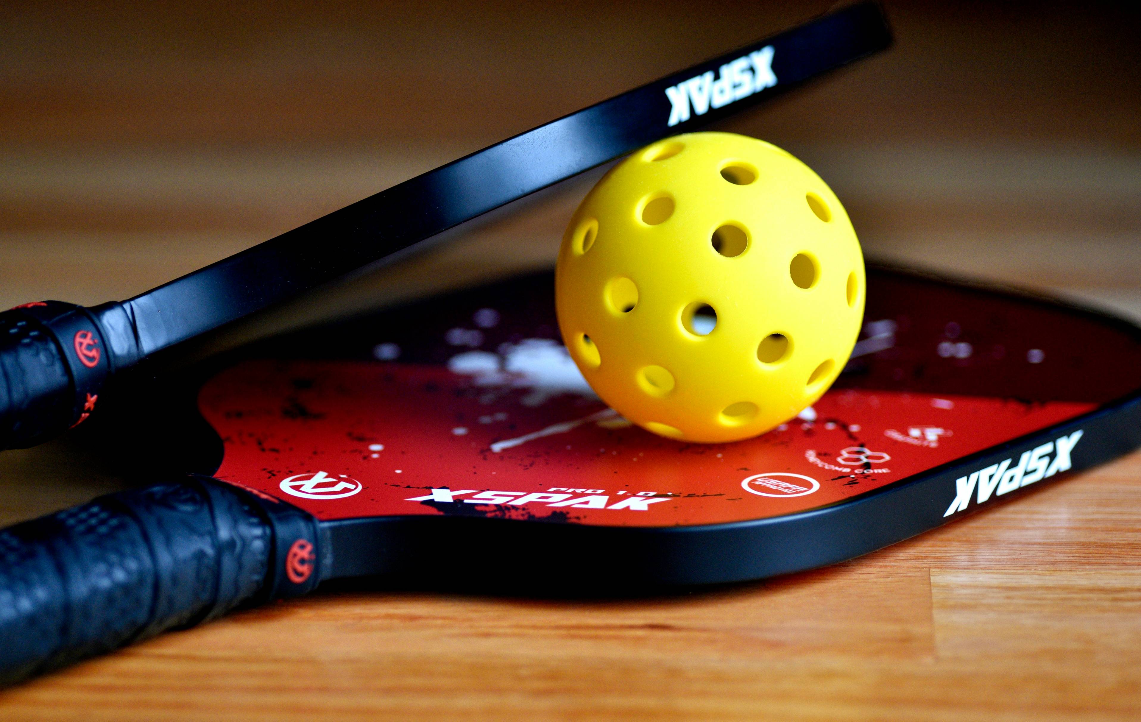 a yellow tennis ball sitting on top of a racket