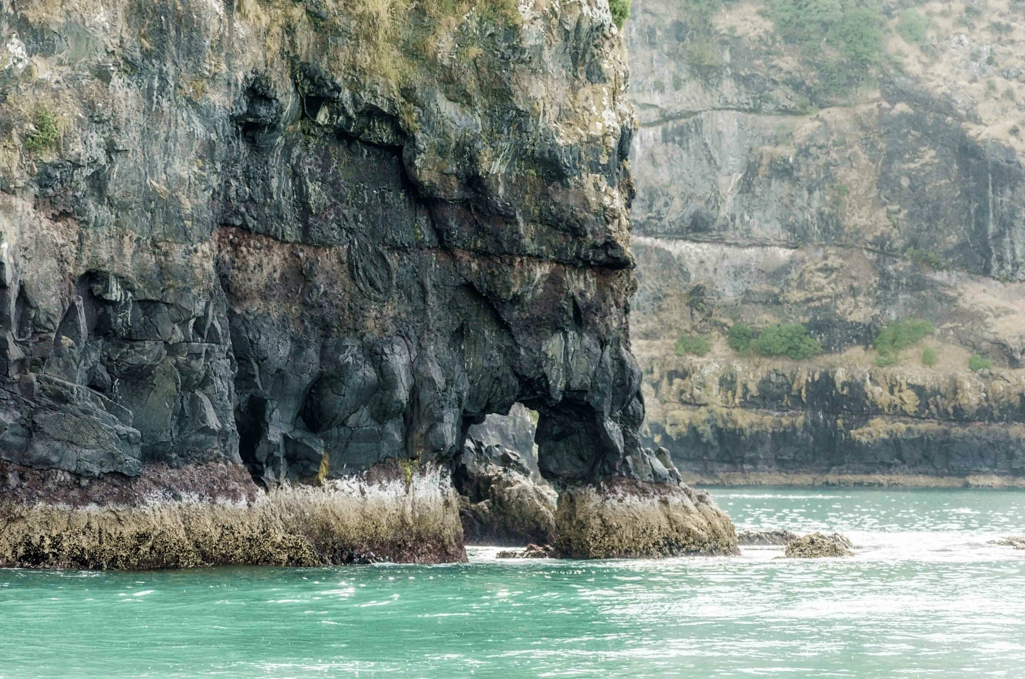 brown rock formation beside body of water during daytime